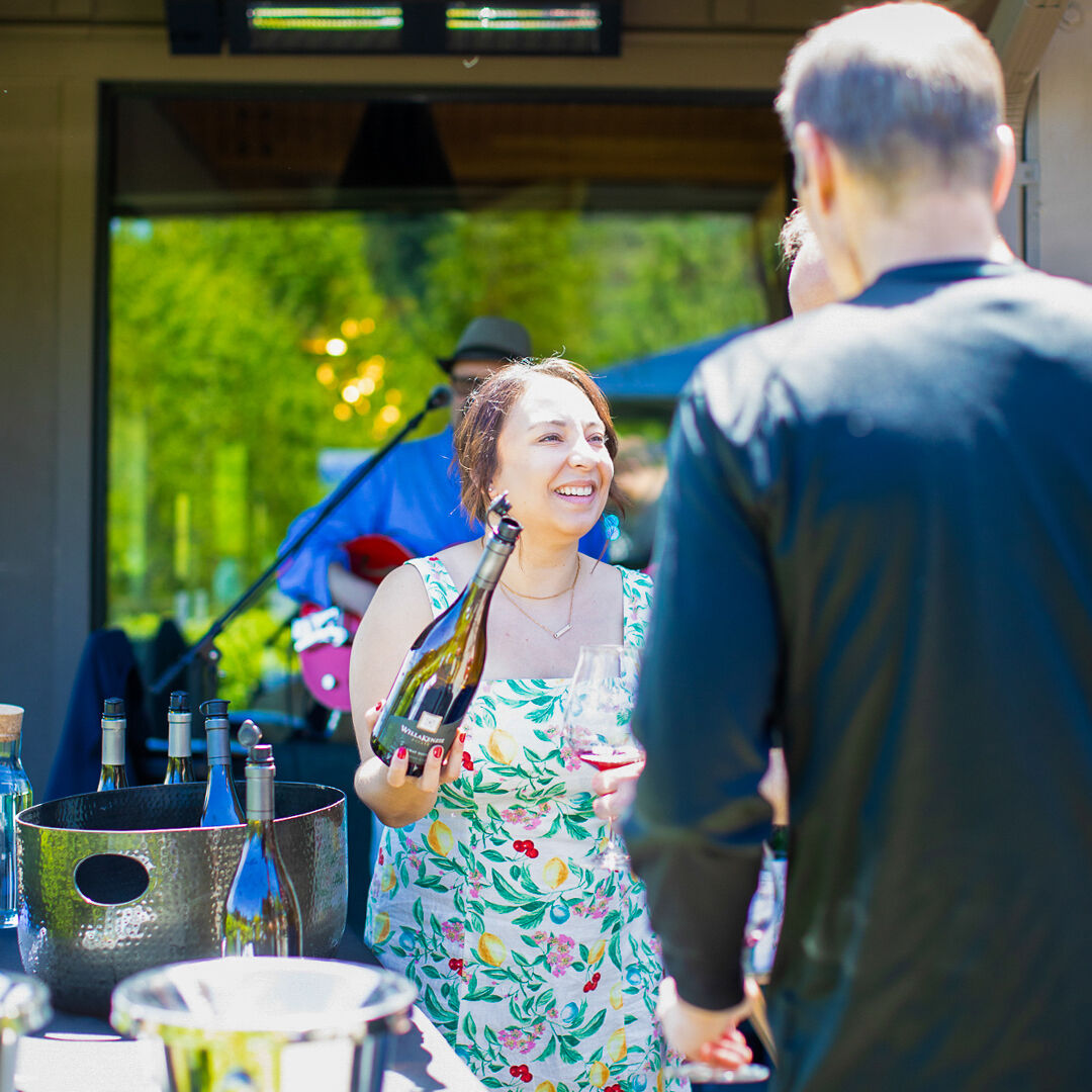 Sydney McMurry assisting guests in front of WillaKenzie with bottle in hand